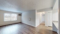 Located at 345 Firwood Dr in Dayton, OH, this single-floor unit combines classic character with updated finishes throughout its well-designed layout. The living area serves as a focal point of the space, showcasing a striking exposed brick accent wall that adds warmth and texture alongside smooth, neutral-painted walls. Wood-style flooring runs consistently throughout the unit, contributing to a cohesive and polished aesthetic. Natural light filters in through multiple windows fitted with blinds, offering views of the surrounding wooded scenery. Wall-mounted air conditioning units and baseboard heating provide year-round climate control.

The kitchen features white cabinetry with modern hardware, granite-look countertops with an integrated sink, and a full-size stainless steel refrigerator, all set atop lighter wood-style flooring. A peninsula counter connects the kitchen to the adjacent living and dining area. The bedrooms are generously proportioned, each offering ample wall space, wood-style flooring, and windows that invite natural light. The bathroom is cleanly finished with a white vanity, white quartz-style countertop, a framed mirror with brushed gold accents, and wood-look flooring, presenting a fresh and functional design.