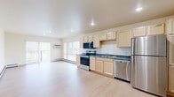 Located at 601 Center Ave in Moorhead, MN, this 2-bedroom, 1-bathroom unit offers a well-organized, single-floor layout designed for comfortable everyday living. Light-toned hardwood flooring runs throughout, creating a clean and cohesive aesthetic across all rooms. The open-concept kitchen and living area form the heart of the unit, with the kitchen featuring light maple cabinetry, dark countertops, stainless steel appliances including a refrigerator, dishwasher, and range, plus recessed overhead lighting. The living room is bright and airy, with sliding glass doors opening to a private balcony, allowing natural light to fill the space and providing outdoor views. Baseboard heating is present throughout. The spacious primary bedroom includes dual windows that bring in additional natural light, while the second bedroom offers similar warmth and simplicity. The full bathroom is finished with a light maple vanity, a wide mirror, and a well-lit vanity fixture. A dedicated in-unit laundry room accommodates a full-size washer and dryer with overhead shelving for added storage. A closet provides further organizational convenience. The unit's neutral palette and consistent finishes give it a clean, functional character throughout.