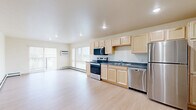 Located at 601 Center Ave in Moorhead, MN, this 2-bedroom, 1-bathroom unit offers a well-organized, single-floor layout designed for comfortable everyday living. Light-toned hardwood flooring runs throughout, creating a clean and cohesive aesthetic across all rooms. The open-concept kitchen and living area form the heart of the unit, with the kitchen featuring light maple cabinetry, dark countertops, stainless steel appliances including a refrigerator, dishwasher, and range, plus recessed overhead lighting. The living room is bright and airy, with sliding glass doors opening to a private balcony, allowing natural light to fill the space and providing outdoor views. Baseboard heating is present throughout. The spacious primary bedroom includes dual windows that bring in additional natural light, while the second bedroom offers similar warmth and simplicity. The full bathroom is finished with a light maple vanity, a wide mirror, and a well-lit vanity fixture. A dedicated in-unit laundry room accommodates a full-size washer and dryer with overhead shelving for added storage. A closet provides further organizational convenience. The unit's neutral palette and consistent finishes give it a clean, functional character throughout.