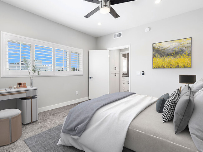 Carpeted bedroom with ceiling fan and large windows for natural light. - South Hayworth Lofts