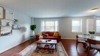 This thoughtfully designed single-floor residence offers a cohesive blend of comfort and style across its well-organized layout. The living room serves as the heart of the home, bathed in natural light from multiple windows and finished with rich hardwood floors. It features a curated gallery wall, eclectic furnishings, and warm, inviting tones that create an effortlessly stylish atmosphere.

The kitchen is fully equipped with stainless steel appliances, granite countertops, a tile backsplash, and ample white cabinetry, providing both functionality and a clean aesthetic. Multiple windows keep the space bright and airy. A dedicated hallway nook houses a stacked washer and dryer, offering the convenience of in-unit laundry.

The bedroom is a serene retreat, with soft, neutral walls, rich hardwood flooring, and thoughtful decor including a gallery wall arrangement above the bed. A second room, ideal as a guest space or home office, features a large window with greenery views and a versatile daybed setup.

The bathroom is finished with white tile walls, dark slate-toned floor tiles, and a full soaking tub with shower, complemented by a window that brings in natural light. Consistent hardwood flooring and soft gray-blue wall tones tie the entire space together harmoniously.