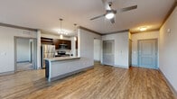 Located at 2560 Judge Fran Jamieson Way in Melbourne, FL, this one-bedroom, two-bathroom residence offers a well-designed single-floor layout with a comfortable and functional living environment. The open-concept kitchen and living area form the heart of the home, featuring warm wood-style flooring, crown molding, and ceiling fans that add a polished touch throughout. The kitchen is equipped with stainless steel appliances, including a refrigerator, range, and built-in microwave, complemented by rich dark-wood cabinetry, granite countertops, a tile backsplash, and a peninsula with pendant lighting — ideal for both cooking and casual dining. The living area is bright and airy, with multiple windows and a glass-panel entry door that welcome abundant natural light and outdoor views. The spacious bedroom features plush carpeting, a ceiling fan, and windows overlooking the surrounding landscape, creating a calm retreat. A hallway connects the bedroom to the bathrooms, one of which serves as an en suite, featuring dark-wood vanity cabinetry with granite countertops and a tiled shower surround. A dedicated closet provides additional storage. The overall aesthetic is modern and cohesive, with neutral tones and quality finishes throughout.