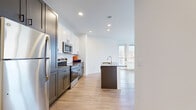 Located at 311 W 22nd St in Kansas City's vibrant Crossroads Arts District, this modern 2-bedroom, 2-bathroom unit offers a thoughtfully designed single-level layout. The open-concept living area seamlessly connects the dining room, kitchen, and living room, all finished with warm light wood flooring that runs throughout. The kitchen is a standout, featuring two-tone cabinetry — crisp white uppers paired with gray lower cabinets — a white subway tile backsplash, dark quartz countertops, stainless steel appliances, and a central island with a built-in sink, ideal for both cooking and entertaining. The primary bedroom offers generous proportions with views of the Kansas City skyline through large windows. The second bedroom features plush carpet and a window overlooking the surrounding urban landscape. A versatile den provides additional flexible space. Both bathrooms are clean and modern, with one featuring a full soaking tub surrounded by classic white subway tile. A dedicated hallway connects the private quarters, and the unit includes in-unit laundry and a utility room for added convenience. Abundant closet space and recessed lighting throughout complete this well-appointed urban residence.