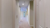 This thoughtfully designed 2-bedroom, 2-bathroom residence offers a practical and comfortable single-floor layout. The combined kitchen and living area serves as the heart of the home. The kitchen is equipped with warm honey-toned cabinetry, dark subway tile backsplash, black appliances including an electric range and refrigerator, and tile flooring. An arched passageway connects the kitchen to the carpeted living room, which features crown molding, a ceiling light fixture, and a glass door providing access to an outdoor balcony with natural light and greenery views. A carpeted hallway with arched architectural details and recessed lighting connects the main living areas to the private quarters. The generously sized primary bedroom includes its own walk-in closet with wire shelving. The second bedroom is also carpeted with a large window allowing ample natural light and access to a dedicated closet. Both bathrooms feature tile flooring and tub-shower combinations with tiled surrounds and chrome fixtures. Throughout the residence, neutral warm beige tones, white trim, and carpet create a cohesive and inviting atmosphere. The layout is efficiently organized, making excellent use of the available space while providing two well-proportioned bedrooms and ample storage.