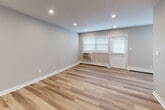 Located at 1710 Devonshire Rd in Hauppauge, NY, this single-floor space has been thoughtfully updated with clean, modern finishes throughout. Light-toned hardwood flooring extends across the main living areas, complementing the soft gray walls and bright white trim to create a cohesive, contemporary aesthetic.

The main living area is open and airy, with recessed lighting illuminating the space alongside natural light from windows fitted with white blinds. A wall-mounted air conditioning unit and baseboard heating provide year-round climate control, while a private entry door adds convenience and accessibility.

An additional room, well-suited for use as a bedroom or flex space, features the same hardwood flooring, neutral walls, and a built-in closet with classic panel doors — offering practical storage solutions. Recessed lighting keeps the room bright and functional.

The bathroom is finished with large-format taupe tile on both the floor and the walk-in shower walls, lending a clean and polished look. A wall-mounted shower head and chrome fixtures add modern detail, while the vanity features a striking granite countertop with subtle veining. A grab bar provides added accessibility. Together, the consistent finishes and well-considered layout make this a move-in ready space.