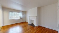 Located in the historic village of Mariemont, Ohio, this one-bedroom, one-bathroom residence offers a thoughtfully arranged single-floor layout with timeless architectural character. The living room serves as the heart of the home, showcasing rich hardwood flooring that extends throughout, a classic white-mantled decorative fireplace as a focal point, and a large multi-pane window that fills the room with natural light. A central hallway connects the living spaces efficiently, with clean white panel doors and crisp trim work lending a cohesive, traditional aesthetic. The bedroom is a comfortable retreat, featuring the same warm hardwood floors and a generously sized window that brings in additional natural light. The galley-style kitchen is efficiently designed with warm wood cabinetry, a white countertop with an integrated sink, tile flooring, and includes a gas range and refrigerator. The bathroom offers a full tub-shower combination with white tile surround, a vanity with under-sink cabinetry, a medicine cabinet mirror, and a window for ventilation. Throughout the space, white walls, consistent trim detailing, and hardwood flooring create a unified, classic ambiance well-suited to the charm of the Mariemont neighborhood.