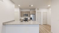 This single-story, 1-bedroom, 1-bathroom unit offers a thoughtfully designed floor plan that maximizes functionality and comfort. The entry features a full-light glass door with blinds, welcoming natural light into the space, complemented by light-toned wood-look flooring that extends throughout the main living areas.

The open-concept kitchen and living room serve as the heart of the unit. The kitchen is equipped with stainless steel appliances, including a refrigerator with ice maker, a range, and a microwave, all set against taupe cabinetry. A granite-topped peninsula island provides additional workspace and doubles as a casual dining or entertaining bar, complete with an undermount sink.

The living area is bright and airy, with multiple windows fitted with blinds and a stylish ceiling fan overhead, creating a comfortable and versatile space.

The bedroom is carpeted for warmth and comfort, featuring two windows that invite natural light, a ceiling fan, and a dedicated closet for ample storage.

The bathroom maintains the unit's consistent aesthetic with granite countertops on the vanity, matching taupe cabinetry, light wood-look tile flooring, and a full tub and shower combination with white tile surround. Clean white walls and recessed lighting throughout lend the entire unit a modern, fresh ambiance.