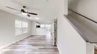 Located in Groveport, Ohio, this two-story home offers a clean, modern aesthetic with thoughtful design across both floors. The main level features an open-concept living area with light-toned luxury vinyl plank flooring, a ceiling fan with integrated lighting, and natural light streaming through multiple windows with blinds. The living room flows seamlessly toward a peninsula-style kitchen, which is equipped with white upper cabinetry, gray lower cabinetry, granite-style countertops, black appliances including a range, built-in microwave, refrigerator, and dishwasher, and recessed lighting throughout. Vertical blinds frame the kitchen windows, adding a bright, airy feel. The upper level is carpeted and hosts both bedrooms, two closets, a hallway, and two full bathrooms. The primary bathroom is a standout feature, boasting a dual-sink vanity with gray countertops, white cabinetry, brushed nickel hardware, and wood-look flooring. The bedrooms are generously proportioned, each with ceiling fans and ample natural light. The primary bedroom includes closet access and a private en-suite bath. A staircase on each floor facilitates smooth vertical circulation throughout this efficiently designed home.