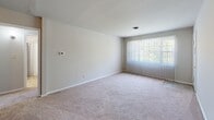 Located at 205 New Castle Dr in Colonial Heights, Virginia, this single-floor home offers a practical and comfortable layout designed for everyday living. The kitchen is well-appointed with white cabinetry, a double-basin sink beneath a window that brings in natural light, tile flooring, and stainless steel appliances including a gas range and a full-size refrigerator. A dedicated laundry room provides added convenience, housing a full-size washer and dryer along with an overhead shelf for storage. The full bathroom features tile flooring, a toilet, and a tub-shower combination. The living area is generously sized, finished with plush carpeting and a large window with vertical blinds that allows ample natural light to fill the room. Multiple bedrooms are carpeted and neutral in tone, each offering a clean, move-in-ready feel. Several bedrooms include closets with built-in hanging rods, providing practical storage solutions. The home maintains a consistent, neutral color palette throughout, creating a bright and cohesive atmosphere. The floor plan, as seen in the overhead doll-house view, reveals a well-organized layout with clear room separation and efficient use of space throughout the single level.