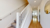 Located at 1898 Zac St in Kissimmee, FL, this two-story home offers three bedrooms and four bathrooms across two floors of thoughtfully designed living space. The exterior presents a clean, modern stucco-and-siding facade with manicured landscaping and a concrete walkway leading to the front entry.

The ground floor centers around an open-concept layout that seamlessly connects the kitchen, dining, and living areas. The kitchen is a standout feature, boasting white shaker cabinetry, a large center island with pendant lighting, stainless steel appliances, and light hardwood-style flooring that extends throughout the main level. A pantry and garage provide added convenience and storage.

Upstairs, the home's three bedrooms are complemented by carpeted floors and an abundance of closet space, including five closets total. The spacious primary bedroom connects directly to a private en-suite bathroom featuring a walk-in glass-door shower with white subway tile. A dedicated laundry room on the upper level houses a full-size washer and dryer. The upper hallway is accented by a white-railed staircase and recessed lighting, creating a bright, open feel throughout. The four bathrooms ensure ample accommodation for residents and guests alike.