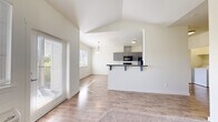 This thoughtfully designed 2-bedroom, 2-bathroom single-floor residence offers a bright and functional open-concept layout. The living area features vaulted ceilings and light-toned hardwood-style flooring that flows throughout the main living spaces, with large windows and a sliding glass door allowing abundant natural light to pour in.

The kitchen is a standout feature, equipped with sleek gray cabinetry, dark granite-style countertops, and a full suite of stainless steel appliances including a range, microwave, dishwasher, and refrigerator. A breakfast bar provides additional seating, while an adjacent dining nook is highlighted by a stylish pendant light and a window with outdoor views.

Both bedrooms are carpeted and well-sized, with the primary bedroom featuring vaulted ceilings and a ceiling fan. The second bedroom benefits from a large window with natural light and closet access. Each bathroom is finished with hexagonal tile flooring, dark countertop vanities, and full mirrors. One bathroom includes a walk-in shower, while the other offers a shower-tub combo.

A dedicated in-unit laundry area with a full-size washer and dryer, along with additional built-in shelving for storage, adds exceptional everyday convenience. The clean, neutral palette throughout creates a bright, move-in-ready atmosphere.