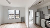 Located in Chicago's vibrant Lakeview neighborhood, this updated unit at 641 W Aldine Ave offers a clean, modern aesthetic throughout. Light hardwood flooring flows seamlessly across the entire space, lending warmth and continuity to every room.

The open living area is bright and airy, featuring large windows with views of the surrounding Chicago cityscape and a classic cast-iron radiator that adds a touch of vintage character. A ceiling fan overhead contributes to year-round comfort. Built-in closet storage keeps the space organized and functional.

The kitchen is well-appointed with gray shaker-style cabinetry, stainless steel appliances including a gas range and full-size refrigerator, a subway tile backsplash with a decorative mosaic accent strip, and a single-basin sink with a brushed nickel faucet. Track lighting illuminates the workspace effectively. The kitchen opens directly to the living area, creating a connected, practical layout.

The bathroom is finished in crisp white tile throughout, featuring a soaking tub with overhead shower, a gray vanity with a white basin sink, brushed nickel hardware, a medicine cabinet mirror, and a frosted window that brings in natural light while maintaining privacy. The classic hex tile flooring adds a subtle, timeless detail to the overall design.