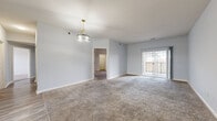 This thoughtfully designed single-floor residence offers three bedrooms, two bathrooms, and a cohesive layout that maximizes comfort and functionality. The living room is generously proportioned, featuring plush wall-to-wall carpeting, soft neutral walls, and sliding glass doors that open onto a private balcony, flooding the space with natural light and offering outdoor views. An elegant pendant light fixture adds a refined touch to the room's clean, open atmosphere.

The kitchen is a standout feature, showcasing a striking two-tone cabinet design with bold navy lower cabinets, crisp white upper cabinets, and gold hardware throughout. Light wood-look flooring, white countertops, and a bright window above the sink complete the modern aesthetic.

Each of the three carpeted bedrooms is bright and well-proportioned, with large windows fitted with blinds that allow for ample natural light and outdoor views. The primary bedroom offers a comfortable and private retreat.

The two bathrooms are finished with gray cabinetry, stone-toned countertops, and wood-look tile flooring. One bathroom includes a full tub-shower combination, while the other features a clean, open layout with a windowed wall for added brightness. Two closets and a hallway round out this well-organized and move-in-ready home.