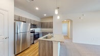 This single-floor residence offers a thoughtfully designed layout with modern finishes throughout. The kitchen serves as a standout feature, showcasing an island with granite countertops and a built-in sink, complemented by stainless steel appliances including a refrigerator, electric range, and microwave. Rich wood-toned cabinetry lines the walls, providing ample storage, while light hardwood flooring and pendant lighting overhead add warmth and style. An elegant arched doorway connects the kitchen to the hallway, lending an architectural detail that enhances the overall flow of the space.

The living area is generously sized, featuring soft carpeting, a ceiling fan, and a sliding glass door that opens to a private balcony with views of the surrounding outdoors. The bedrooms are carpeted and well-lit with natural light streaming through large windows fitted with blinds.

The bathrooms are finished with the same granite countertops found in the kitchen, wood-toned vanity cabinetry, hardwood-style flooring, and large mirrors. One bathroom includes a full soaking tub with shower, while another features a spacious vanity with overhead cabinetry. Throughout the residence, consistent finishes and a neutral color palette create a cohesive and inviting atmosphere.