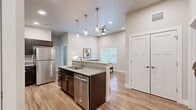 Located at 200 S 4th St in Lafayette, Indiana, this thoughtfully designed 2-bedroom, 2-bathroom unit offers a modern and functional layout across a single floor. The open-concept living and kitchen area serves as the heart of the home, featuring warm wood-style flooring, recessed lighting, and tall ceilings that lend an airy, spacious feel. The kitchen is well-appointed with dark espresso cabinetry, granite countertops, a full suite of stainless steel appliances, and a peninsula with bar seating illuminated by pendant lighting — ideal for casual dining or entertaining. The living room flows naturally from the kitchen, offering a bright window that draws in natural light and ample space for comfortable furnishings. Both bedrooms feature plush carpeting, generous ceiling heights, and access to closet space. The primary bedroom includes dual doorways leading to a closet and en-suite bath. Each bathroom is finished with dark vanity cabinetry, granite countertops, and wood-style tile flooring, with one bath featuring a shower/tub combination. The unit's neutral color palette and consistent, contemporary finishes create a cohesive and welcoming ambiance throughout.