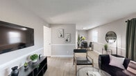 This thoughtfully laid-out 2-bedroom, 1-bathroom residence offers a functional and stylish single-floor living experience. The open-concept living, dining, and kitchen area serves as the heart of the home, finished in a neutral gray palette with crisp white trim and light wood-style flooring that flows seamlessly throughout. The living room features a sliding glass door with vertical blinds and curtain panels, allowing natural light to fill the space. The kitchen is outfitted with dark shaker-style cabinetry, white countertops, and a full suite of stainless steel appliances, including a dishwasher, range, and built-in microwave. The adjacent dining area benefits from a window that brings in additional natural light. The primary bedroom offers a generous layout with a bold blue accent wall, a wide sliding-door closet, and light-filled windows. The second bedroom is bright and comfortable, featuring a closet and natural light from a windowed wall. The full bathroom includes a tiled shower-tub combination, wood-style flooring, a white vanity, and a textured ceiling. A connecting hallway ties the private rooms together efficiently, completing this well-organized and move-in-ready floor plan.