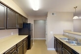 Located at 19311 Votrobeck Dr in Detroit, Michigan, this single-floor, 2-bedroom, 1-bathroom home offers a functional and well-organized layout. The entrance leads into a combined living and dining area that provides a comfortable, open gathering space with natural light filtering through vertical blinds. The galley-style kitchen is efficiently designed, featuring dark wood cabinetry lining both walls, light countertops, black appliances including a gas range, dishwasher, and refrigerator, and a double sink. A window at the end of the kitchen brings in additional natural light. Both bedrooms are carpeted and finished in warm neutral tones, each offering a windowed wall with vertical blinds. The primary bedroom includes dedicated closet space, while the second bedroom also benefits from its own closet. Notably, the home features an impressive five closets throughout, providing generous storage options. A hallway connects the main living areas to the bedrooms and the full bathroom, which includes a tiled tub-shower combination with clean white subway tile surround. The neutral color palette, consistent flooring, and practical layout make this a comfortable and move-in-ready home.