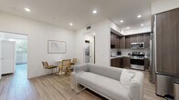 Located in the heart of Los Angeles, this single-story home offers four bedrooms and two bathrooms across a well-designed floor plan. The open-concept living area features light wood-look flooring, recessed lighting, and crisp white walls that create a clean, modern aesthetic. A wall-mounted TV and a comfortable seating arrangement make the living space both functional and inviting.

The kitchen is a standout feature, showcasing dark wood cabinetry that extends floor to ceiling, white quartz countertops, a decorative tile backsplash, and a full suite of stainless steel appliances including a gas range, microwave, and refrigerator.

The generously sized primary bedroom offers ample space, a sliding mirrored closet, and large windows that frame views of lush greenery. The additional bedrooms maintain the same clean design language with wood-look flooring and well-sized windows that bring in natural light. A dedicated walk-in closet with built-in shelving and drawers provides excellent storage.

Both bathrooms are tastefully finished, featuring wood-toned vanities with white countertops and large mirrors. One bathroom includes patterned tile flooring and a frameless sliding glass shower enclosure with a soaking tub, while the second offers a similar tub-shower combination with neutral tile surround.