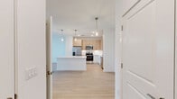Located at 1305 Farkleberry Ln in Davenport, FL, this thoughtfully designed one-bedroom, two-bathroom residence offers a clean, modern aesthetic throughout its efficiently laid-out single floor. Light wood vinyl flooring flows seamlessly across every room, creating a bright and cohesive atmosphere.

The open-concept kitchen and living area serves as the heart of the home. The kitchen is equipped with stainless steel appliances — including a French door refrigerator, range, microwave, and dishwasher — complemented by light wood cabinetry, white lower cabinets, and a crisp white quartz countertop. A large central island with pendant lighting above provides both additional prep space and a natural gathering point.

The living area features direct access to a private outdoor space through a glass door, with windows allowing natural light to fill the room. The generously sized primary bedroom includes a ceiling fan, a wide window with outdoor views, and direct access to a well-appointed en suite bathroom. The en suite features a light wood vanity with quartz countertops, a soaking tub, and a tiled shower. A second bathroom offers convenience for guests. The overall ambiance is clean, contemporary, and move-in ready.