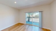 Located at 2301 Ulric St in San Diego, CA, this thoughtfully designed studio offers a clean, modern aesthetic across a single floor. The open-concept layout seamlessly combines the kitchen and living area, maximizing the efficient use of space. Light-toned hardwood flooring runs throughout, lending warmth and continuity to the interior. Recessed lighting illuminates the living area, which features crisp white walls and a sliding glass door that opens to a private balcony with views of surrounding palm trees — bringing a distinctly Southern California ambiance to the space.

The kitchen is well-appointed with bright white shaker-style cabinetry, a white subway tile backsplash, and a full suite of stainless steel appliances, including a refrigerator, electric range, over-the-range microwave, and dishwasher. Light quartz countertops complete the contemporary look, making this kitchen as functional as it is stylish.

The bathroom continues the modern design language with a large walk-in shower enclosed by sliding glass doors with bold matte black hardware and framing, set against clean white walls. The overall ambiance of the space is bright, fresh, and move-in ready, reflecting a newly updated interior ideal for comfortable urban living in San Diego.