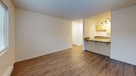 Located at 2600 T St in Vancouver, WA, this efficient one-bedroom, one-bathroom unit offers a well-organized layout across a single floor. Wood-look flooring flows consistently throughout the space, lending a cohesive and clean aesthetic to every room.

The living room is a bright, open area anchored by two large windows fitted with blinds, allowing natural light to fill the space while offering views of the surrounding neighborhood. A baseboard heating system runs along the walls, and a textured ceiling adds subtle character. The living room connects seamlessly to the kitchen via a half-wall peninsula with a dark laminate countertop, creating an open and functional feel.

The kitchen is efficiently designed with light wood cabinetry on both upper and lower sections, dark laminate countertops with a decorative tile backsplash accent, and white appliances including an electric range and full-size refrigerator. Wood-look tile flooring completes the kitchen's practical and tidy finish.

The bedroom is a comfortable, well-lit room featuring a window with blinds, baseboard heating, and a sliding double-panel closet for ample storage. The textured ceiling is consistent with the rest of the unit.

The bathroom includes a full tub-shower combination with clean white surround, a wood-vanity with a laminate countertop and under-sink storage, and matching wood-look flooring. A hallway with additional closet space connects the main areas of the unit efficiently.