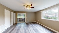 Located at 1005 McCord Rd in Valparaiso, Indiana, this single-story home offers a well-maintained, move-in-ready interior with a cohesive and neutral aesthetic throughout. The entire home is finished with modern luxury vinyl plank flooring in a light gray wood tone, providing both durability and a clean, contemporary look.

The main living area is generously proportioned, featuring warm tan walls, white trim, and a ceiling fan with light fixture overhead. Large sliding glass doors open directly to the backyard, flooding the space with natural light and offering easy outdoor access. An adjacent window further enhances brightness. The layout connects seamlessly to a kitchen area, which is visible with white cabinetry and stainless steel appliances.

The bedrooms continue the same flooring and neutral wall palette. Each room is equipped with a ceiling fan and windows that allow natural light and outdoor views. One bedroom features a double-door closet, providing ample storage. The rooms offer a comfortable and functional layout suitable for a variety of furnishing arrangements.

The bathroom is finished in crisp white, featuring a full tub and shower combination with a white surround, a white vanity with cabinet storage, and brushed nickel hardware and fixtures. The consistent flooring carries through here as well, tying the space together. Overall, the home presents a tidy, functional, and welcoming environment.