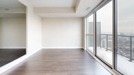 Located at 561 Sherbourne St in Toronto's vibrant St. James Town neighbourhood, this one-bedroom, one-bathroom unit offers a thoughtfully designed layout with modern finishes throughout. The living area is highlighted by expansive floor-to-ceiling sliding glass doors that open to a balcony, flooding the space with natural light and framing sweeping views of the Toronto skyline, including a clear sightline to the CN Tower. Dark-toned hardwood flooring runs throughout the living and bedroom areas, contrasting cleanly against neutral, light-toned walls and white baseboards for a crisp, contemporary aesthetic. A tray ceiling detail in the living room adds a subtle architectural element. The bedroom is a well-proportioned private retreat, also featuring a large window with city views and the same hardwood flooring, creating a cohesive feel. The bathroom is finished with large-format grey tile flooring, a dark espresso-toned vanity with an integrated sink, and a full soaker tub with a tiled surround and curved shower rod. The overall design is clean, minimal, and modern, making efficient and stylish use of the available space while offering an elevated urban living experience high above the city.