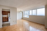 Located at 210 Steeles Ave W in Brampton, Ontario, this 2-bedroom, 1-bathroom unit offers a practical and well-organized layout across a single floor. Warm parquet flooring flows consistently throughout the living areas, hallways, and bedrooms, lending a cohesive character to the space.

The living area is bright and open, benefiting from a large corner window that invites generous natural light and frames open outdoor views. A pendant light fixture adds a simple decorative touch overhead. The kitchen is positioned adjacent to the living space and features rich wood-toned cabinetry spanning both upper and lower sections, a double stainless steel sink, tile flooring, and ample counter space — providing a functional cooking environment.

Both bedrooms are well-proportioned, with the primary bedroom offering notable space, large windows with expansive views, and parquet flooring. The second bedroom includes sliding wood-panel closet doors, providing practical built-in storage. A hallway connects the rooms efficiently, maintaining a clean and straightforward flow throughout the unit.

The bathroom is finished with a full-sized bathtub and tiled surround featuring a classic patterned design, complemented by a handheld showerhead. Two hallways guide movement through the unit, contributing to its organized feel. Overall, the space presents a functional and comfortable layout suited for everyday living.