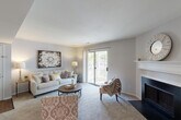 Located at 1126 Bonhomme Lake Dr in Olivette, Missouri, this single-floor, 2-bedroom, 2-bathroom residence offers a thoughtfully designed layout that balances comfort and functionality. The living room serves as the heart of the home, highlighted by a classic fireplace with a white mantel, soft carpeting, and a sliding glass door that opens to a private balcony overlooking lush, mature trees — filling the space with natural light and outdoor views. The adjacent dining area features track lighting overhead and connects seamlessly to the rest of the living space, creating an easy flow for daily living and entertaining. The kitchen is equipped with warm wood cabinetry, black appliances, and a generous granite-style breakfast bar with seating, complemented by a pass-through window that maintains an open connection to the living areas. The primary bedroom offers comfortable proportions with plush carpet, a mirrored sliding closet, and ample storage. The second bedroom is bright and inviting, with a large window that brings in natural light. Both bathrooms are well-appointed; one features a dual-sink vanity with wood cabinetry and hardwood flooring, alongside a tub-shower combination. Together, the rooms create a cohesive, comfortable living environment in a serene Olivette setting.
