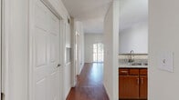 This single-floor, one-bedroom, one-bathroom residence offers a thoughtfully organized layout that maximizes functionality throughout. The interior is characterized by a clean, neutral color palette with white walls, providing a bright and airy atmosphere.

The kitchen is well-equipped with warm-toned wood cabinetry, granite-style countertops, a tile backsplash, and a full suite of black appliances including a refrigerator, range, over-the-range microwave, and dishwasher. Light ceramic tile flooring completes the space. Adjacent to the kitchen, a hallway leads to the main living area, where rich hardwood-style flooring extends throughout and a sliding glass door opens to an outdoor balcony, allowing natural light to fill the room.

The bedroom is a comfortable retreat featuring plush carpeting, a ceiling fan with light fixture, and access to two closets — including a spacious walk-in closet outfitted with wire shelving systems. The bathroom includes a full tub and shower combination with floor-to-ceiling tile surround, ceramic tile flooring, warm wood cabinetry, and chrome fixtures. A textured ceiling is a consistent architectural detail present throughout the residence. Two closets provide ample additional storage space.