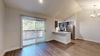 This 1-bedroom, 1-bathroom unit offers a thoughtfully designed layout across a single floor, maximizing functionality and comfort. The combined kitchen and living area serves as the heart of the home, featuring vaulted ceilings that lend an airy, open feel. Warm wood-look flooring runs throughout, complementing the neutral color palette. A tiled fireplace serves as a focal point in the living room, adding both style and warmth, while a chandelier overhead adds a decorative touch. Sliding glass doors flood the living space with natural light and open directly onto a private patio, offering pleasant outdoor views of surrounding greenery.

The kitchen is equipped with stainless steel appliances, including a refrigerator, range, and microwave, and features dark cabinetry with a tile backsplash. A peninsula with a light stone countertop and integrated sink provides additional prep space and casual seating.

The bedroom is a comfortable, well-lit retreat with a ceiling fan, a window with blinds, and direct access to two closets, one of which includes built-in shelving and hanging rods for ample storage. The bathroom offers a full tub-and-shower combination with floor-to-ceiling tile surround and wood-look flooring. A hallway connects the rooms efficiently, completing this cohesive and practical floor plan.