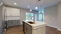 Located at 3125 Fire Ct in Charlotte, NC, this single-floor residence offers a thoughtfully designed open-concept layout with contemporary finishes throughout. The kitchen serves as a central highlight, featuring a large center island with a white quartz countertop, an undermount sink with a brushed gold faucet, and two-tone cabinetry pairing crisp white upper cabinets with soft gray lower cabinets. A classic white subway tile backsplash complements the full suite of stainless steel appliances, including a refrigerator, range, and built-in microwave. Pendant lighting above the island adds a warm, refined touch. The kitchen flows seamlessly into the open living and dining areas, where warm-toned hardwood-style flooring extends throughout, and a pendant light fixture adds character to the transition space.

The bedrooms are generously sized, fitted with plush carpet and ceiling fans, and benefit from large windows that frame lush outdoor greenery, filling each room with natural light. The bathrooms maintain the home's cohesive aesthetic, featuring gray vanity cabinetry with white countertops, wood-look flooring, and tub-shower combinations with clean white tile surrounds. Neutral wall tones and consistent design details create a calm, polished ambiance throughout the entire home.