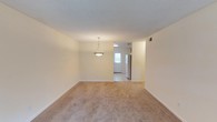 Located at 4344 Langley Ave. in Pensacola, Florida, this single-floor residence offers a straightforward and functional layout designed for comfortable everyday living. The main living area features warm, neutral-toned carpet flooring and cream-colored walls that create a bright, welcoming atmosphere. A textured ceiling adds subtle character to the space, while a pendant light fixture serves as a focal point, providing both style and illumination. The open flow of the layout connects the living area directly to the kitchen, which transitions to tile flooring and is equipped with a full-size refrigerator. A glass-paneled exterior door in the kitchen area allows natural light to filter into the space, enhancing the overall brightness of the interior. The clean, neutral color palette throughout the home provides a versatile backdrop suitable for a variety of interior styles. With its efficient single-level design and practical features, this Pensacola residence offers a comfortable and accessible living environment in a well-located neighborhood.