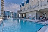 Located in the heart of Atlanta's Old Fourth Ward at 100 Sixth St NE, this rooftop amenity deck offers an elevated urban retreat with stunning panoramic views of the Atlanta skyline. The outdoor space centers around a sparkling swimming pool with a shallow entry and glass perimeter railings that preserve unobstructed sightlines of the surrounding cityscape, including iconic downtown high-rises.

A generously sized sun terrace lines the pool deck, furnished with contemporary reclining loungers accented with teal and striped cushions, ideal for relaxing in the open air. The rooftop also features a dedicated covered lounge area that transitions seamlessly from interior to exterior. This shaded zone is appointed with wicker seating arrangements, colorful area rugs, and lush potted plants, creating a comfortable and stylish gathering space. A distinctive sculptural chair adds a playful design accent to the lounge.

The deck's concrete and tile surfaces are well-maintained and thoughtfully laid out to accommodate both active poolside use and quieter relaxation. Additional seating nooks with dark armchairs are positioned to take full advantage of the sweeping open-air views. The combination of modern furnishings, resort-caliber amenities, and direct views of the Atlanta skyline makes this rooftop deck a standout feature of the property.