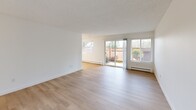 Located in Seattle's desirable Magnolia neighborhood, this well-appointed 2-bedroom, 3-bathroom residence offers a clean, modern aesthetic across a single thoughtfully designed floor. Light-toned luxury vinyl plank flooring flows consistently throughout, complementing the bright white walls and creating a cohesive, airy atmosphere.

The galley-style kitchen is a standout feature, outfitted with crisp white shaker cabinetry, matte black hardware, white quartz countertops, and a full suite of stainless steel appliances including a refrigerator, electric range, and dishwasher. Flush panel lighting illuminates the space efficiently. The kitchen opens toward a combined dining and living area, which benefits from generous natural light and sliding glass doors that provide direct access to an outdoor patio with greenery views.

Both bedrooms are well-sized with large windows framing leafy outdoor scenery, light-filled interiors, and baseboard heating. The spacious primary bedroom offers ample room for furnishings. Five closets distributed throughout the unit provide exceptional storage capacity.

All three bathrooms are finished in a clean, contemporary style featuring white vanities with quartz counters, matte black fixtures, and light wood-tone flooring. Bathroom configurations include a soaking tub combo and a dedicated glass-enclosed walk-in shower. A central hallway connects the living spaces to the private bedroom wing, completing the functional and efficient layout.