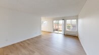 Located in Seattle's desirable Magnolia neighborhood, this well-appointed 2-bedroom, 3-bathroom residence offers a clean, modern aesthetic across a single thoughtfully designed floor. Light-toned luxury vinyl plank flooring flows consistently throughout, complementing the bright white walls and creating a cohesive, airy atmosphere.

The galley-style kitchen is a standout feature, outfitted with crisp white shaker cabinetry, matte black hardware, white quartz countertops, and a full suite of stainless steel appliances including a refrigerator, electric range, and dishwasher. Flush panel lighting illuminates the space efficiently. The kitchen opens toward a combined dining and living area, which benefits from generous natural light and sliding glass doors that provide direct access to an outdoor patio with greenery views.

Both bedrooms are well-sized with large windows framing leafy outdoor scenery, light-filled interiors, and baseboard heating. The spacious primary bedroom offers ample room for furnishings. Five closets distributed throughout the unit provide exceptional storage capacity.

All three bathrooms are finished in a clean, contemporary style featuring white vanities with quartz counters, matte black fixtures, and light wood-tone flooring. Bathroom configurations include a soaking tub combo and a dedicated glass-enclosed walk-in shower. A central hallway connects the living spaces to the private bedroom wing, completing the functional and efficient layout.