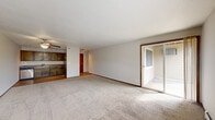 Located in Little Canada, Minnesota, this single-floor, 2-bedroom, 2-bathroom unit offers a practical and comfortable layout designed to maximize everyday livability. The open-concept kitchen and living area forms the heart of the home, where warm hardwood flooring anchors the kitchen, outfitted with rich dark wood cabinetry, granite-toned countertops, stainless steel appliances including a range, dishwasher, and refrigerator, plus a track lighting fixture overhead. The spacious living room is finished with plush carpet, a ceiling fan, and large windows that allow generous natural light to fill the room. A sliding glass door provides direct access to an outdoor area and further brightens the space. Both bedrooms are carpeted and offer closet storage, with the primary bedroom being notably spacious. The two bathrooms feature dark wood vanities with wide mirrors, lighted fixtures, and tiled tub-shower combinations. A baseboard heating system and wall-mounted AC units are present throughout. The overall aesthetic is clean and neutral, with white walls, wood-toned accents, and a functional design well-suited to everyday living in the Little Canada community.