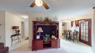 This single-story home on Buffalo Church Rd in Sanford, NC offers a comfortable and well-organized layout designed for everyday living. The living room is an inviting space featuring carpet flooring, a ceiling fan with light fixture, and a textured ceiling. A large entertainment center serves as a focal point, while the open sightline connects seamlessly to the dining area, which is brightened by natural light from multiple windows framed with warm-toned drapes and includes convenient pantry storage nearby. The kitchen is well-equipped with white cabinetry, white appliances including a refrigerator, dishwasher, and built-in cooktop, complemented by a double sink and tile flooring. The primary bedroom is generously sized with plush carpeting, multiple windows that allow ample natural light, and ample space for a sitting area and full dresser suite. A secondary bedroom offers a comfortable retreat with carpet flooring, a window, and closet access. The home includes two full bathrooms, each featuring a tub-shower combination and tile flooring. Throughout, the interior presents a consistent warm neutral color palette, textured ceilings, and a cohesive, lived-in character that makes this home feel inviting and functional.