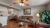 This single-story, 3-bedroom, 2-bathroom home offers a thoughtfully arranged layout that maximizes every square foot. Rich hardwood-style flooring flows through the living, dining, and kitchen areas, creating a warm and cohesive atmosphere throughout the common spaces.

The living room is an inviting gathering space, featuring a ceiling fan with light fixture, neutral warm-toned walls, and a window that allows natural light to brighten the room. It opens seamlessly into the dining area, which accommodates a glass-top oval dining table and wooden chairs, accented by chair rail molding along the walls.

The galley-style kitchen is efficiently designed with ample warm wood cabinetry, granite-look countertops, tile backsplash, and black appliances including a refrigerator and electric range, with hardwood-style flooring completing the look.

The primary bedroom offers a comfortable footprint with carpet flooring, a window with blinds providing natural light, and room for a dresser and mirror. The additional bedrooms are similarly carpeted and neutrally toned, offering versatile spaces. The bathrooms feature granite-look countertops with undermount sinks and wood cabinetry, providing a clean and functional finish. This home combines practical design with warm, classic detailing throughout.
