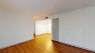 This single-floor space offers a well-organized layout with a clear distinction between living and sleeping areas. The main living area features warm-toned hardwood-style flooring that extends through the open-plan space, with a connected dining area illuminated by a pendant light fixture. A large sliding glass door with vertical blinds allows generous natural light into the living room while providing outdoor access. A closet with paneled doors adds practical storage to the living space.

The kitchen is thoughtfully updated, showcasing dark espresso-toned cabinetry with brushed nickel hardware, crisp white countertops, and a classic white subway tile backsplash. A stainless steel Whirlpool range with an overhead ventilation hood serves as the kitchen's focal point, complemented by hardwood-style flooring underfoot.

The bedrooms are carpeted with neutral tones and receive natural light through windows fitted with horizontal blinds. One bedroom includes a walk-in closet, offering additional storage capacity. Both rooms feature textured ceilings and clean white walls.

The bathroom presents a refined, updated aesthetic with dark marble-style tile flooring, a white subway-tiled tub and shower combination with a rainfall showerhead, and a vanity topped with a framed mirror.