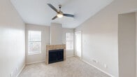Located at 10300 Golden Meadow Dr in Austin, TX, this one-bedroom, one-bathroom unit offers a thoughtfully laid-out single-floor plan with a comfortable, functional design throughout. The living room serves as the centerpiece of the home, highlighted by a tile-surround wood-burning fireplace, vaulted ceilings, and a ceiling fan with light fixture. Multiple windows dressed with blinds allow natural light to fill the space, while plush carpeting adds warmth underfoot. A door leads directly to a private patio, extending the living area outdoors. The kitchen features an efficient galley-style layout with white cabinetry, light countertops, a built-in sink, and stainless steel appliances including a refrigerator, range, and microwave. Light wood-look flooring flows through the kitchen and dining area, which opens seamlessly via a breakfast bar to the main living space. The bedroom is generously proportioned, carpeted, and equipped with a ceiling fan and a sliding glass door offering outdoor views. A walk-in closet provides dedicated storage. The bathroom includes a full tub-shower combination with white tile surround. Neutral tones and clean finishes throughout lend the space a move-in-ready, understated appeal.