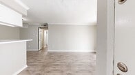 This single-story, 2-bedroom, 1-bathroom residence offers a thoughtfully organized layout designed for comfortable everyday living. The open-concept living, dining, and kitchen area forms the heart of the home, featuring light wood-look flooring, neutral gray walls, crown molding, and a textured ceiling. Large sliding glass doors flood the living space with natural light while providing access to the outdoors. The galley-style kitchen is equipped with white cabinetry, white countertops, a built-in sink, and black appliances including a refrigerator, range, and dishwasher — offering a clean, functional workspace. Both bedrooms are carpeted and finished in soft neutral tones. The primary bedroom is generously sized, featuring a ceiling fan, a window with natural light, a built-in closet, and direct access to the shared bathroom. The second bedroom also includes closet space and a ceiling fan. The full bathroom features wood-look flooring, a white vanity with a marble-style countertop, and a full tub-shower combo. A notable highlight of this unit is its exceptional storage, with five closets distributed throughout, including a spacious walk-in closet with built-in shelving and hanging rods. A connecting hallway ties the private and shared spaces together seamlessly.