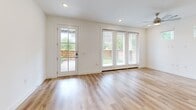 This well-designed two-story home offers a thoughtful layout across two floors, combining modern finishes with functional living spaces. The ground floor features an open-concept kitchen and living area, where light wood-look flooring flows seamlessly throughout. The kitchen is a standout, equipped with stainless steel appliances, a central island with a sink and pendant lighting, a mix of white and warm-toned cabinetry, and open shelving for added character. The living area is bright and airy, with large windows and a glass-paned door that invite abundant natural light and provide views of the outdoors. A hallway with recessed lighting and clean white walls leads to additional spaces, including an attached garage with an automatic door opener. Upstairs, the more expansive floor houses both bedrooms, each featuring plush carpeting, ceiling fans, and multiple windows that frame green outdoor views. The generously sized primary bedroom includes a walk-in closet outfitted with built-in shelving and double hanging rods. The two bathrooms are finished with neutral tile flooring, white cabinetry, quartz-style countertops, and a tiled soaking tub. Throughout the home, a consistent palette of whites and warm neutrals creates a clean, contemporary ambiance.