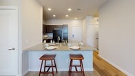 Located at 1100 Avenida Mercado St in Austin, TX, this well-appointed 2-bedroom, 2-bathroom single-story home offers a thoughtfully designed layout with modern finishes throughout. The open-concept kitchen serves as the heart of the home, featuring rich dark cabinetry, granite countertops, black appliances including a range, microwave, refrigerator, and dishwasher, as well as a peninsula island with bar seating — ideal for casual dining or entertaining. Light wood-style flooring extends through the kitchen and living areas, creating a warm, cohesive feel, while recessed lighting and a ceiling fan keep the space bright and comfortable. The living area benefits from natural light streaming in through multiple windows. Both bedrooms are carpeted and equipped with ceiling fans, offering a cozy retreat. The primary bedroom connects to its own bathroom, which features a soaking tub, a granite-topped double vanity with dark cabinetry, and wood-style flooring. The secondary bathroom mirrors the same quality finishes with a tub/shower combination and granite vanity. Each bedroom includes a dedicated closet, with the primary offering a walk-in. A connecting hallway ties all rooms together in a practical and efficient floor plan.