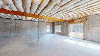 Located at 51 Hillside Rd in Pine Plains, NY, this property presents an unfinished basement level offering a generous open-plan footprint with significant potential for customization. The space features poured concrete walls and a smooth concrete slab floor, providing a solid structural foundation throughout. Exposed wood floor joists above are fully insulated with spray foam and batt insulation, contributing to energy efficiency while keeping the ceiling height comfortable and functional. Steel lally columns are positioned throughout the open area, supporting the structure above. Natural light enters through multiple windows along the concrete walls, as well as a sliding glass door that opens to the outdoors, offering views of the surrounding Pine Plains landscape. A wood-framed staircase with framed enclosure provides interior access to the floor above, and the utility area is visible with a water heater already in place. Partial wood stud framing is underway in select areas, suggesting the groundwork for future room divisions. The overall layout is expansive and clear-span, making it well-suited for a wide range of finishing possibilities, from additional living space to recreation or storage use. The space reflects a clean, well-structured shell ready for the next phase of development.