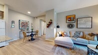 This single-floor residence offers a well-organized layout that balances open communal spaces with private retreats. The living area is generously proportioned, featuring light wood-look flooring, a ceiling fan, and a sliding glass door that invites natural light and provides outdoor views. A compact dining area sits adjacent to the living space, creating a seamless flow ideal for everyday living and entertaining.

The kitchen is designed with functionality in mind, featuring U-shaped cabinetry finished in warm wood-tone laminate, granite-look countertops, a double-basin sink, and a full suite of white appliances including a refrigerator, range, microwave, and dishwasher. Light flooring continues throughout, maintaining visual cohesion.

Two bedrooms offer comfortable, carpeted retreats, each with windows dressed in vertical blinds and sheer curtains that allow natural light while maintaining privacy. The bathroom includes a granite-topped vanity with wood-tone cabinetry, light wood flooring, a shower-tub combination, and a high horizontal window that brings in additional daylight. A tiered wooden wall shelf in the hallway adds a distinctive decorative touch throughout the space.