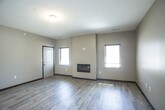 This 3-bedroom, single-floor unit is designed with a contemporary, functional layout that balances open communal spaces with private retreats. The open-concept living and dining area features smooth hardwood-style flooring, neutral-toned walls, and two windows that allow natural light to fill the space. A built-in electric fireplace serves as a focal point along one wall, adding both warmth and visual interest.

The kitchen is equipped with rich dark cabinetry, granite countertops, and a full suite of black appliances including a refrigerator with ice maker, electric range, and built-in microwave. Pendant lighting illuminates a breakfast bar peninsula that connects the kitchen to the main living area, offering additional seating and counter space.

A hallway leads to three carpeted bedrooms, each offering generous proportions. One bedroom includes a closet with bi-fold doors and a built-in rod system. The bathrooms feature dark wood cabinetry, granite-topped vanities, large mirrors, and tile flooring. One bathroom includes a tub-shower combination, while another offers a separate toilet room for added privacy.

A dedicated laundry room with side-by-side washer and dryer and built-in shelving completes the practical layout of this well-finished space.