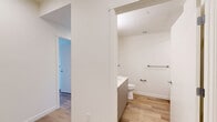 Located at 18807 8th Ave NE in Shoreline, WA, this thoughtfully designed 2-bedroom, 2-bathroom residence offers a clean, modern aesthetic throughout its single-floor layout. Light-toned hardwood flooring flows consistently across all rooms, creating a cohesive and bright atmosphere.

The open kitchen and living area serve as the heart of the home. The kitchen is outfitted with stainless steel appliances — including a refrigerator, electric range, microwave, and dishwasher — complemented by warm wood upper cabinetry, gray lower cabinets, and a subtle tile backsplash. Recessed lighting and a large window with plantation shutters fill the space with natural light.

The living room offers a clean, open canvas with neutral walls, additional windows, and direct access to a private balcony through sliding glass doors — bringing in views of the surrounding greenery. A ceiling fan adds both function and style.

The primary bedroom is comfortably sized, featuring a ceiling fan, a sliding glass door to the balcony, and ample natural light. The second bedroom includes a built-in closet with sliding doors. Both bathrooms are finished with light wood-look tile flooring, modern vanities with white countertops, and accessibility grab bars, reflecting a practical and inclusive design approach. Hallways connect each space efficiently, completing this well-appointed residence.