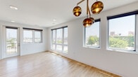 Located at 428 Missouri Ave in St. Louis, Missouri, this single-floor unit showcases a modern, open-concept design with clean lines and contemporary finishes throughout. Light wood-style flooring flows through the main living areas, complementing the crisp white walls and creating a bright, cohesive aesthetic.

The open living and dining area is anchored by large, multi-pane windows that frame elevated views of the surrounding St. Louis cityscape and greenery, flooding the space with natural light. Stylish amber globe pendant lighting adds a warm, designer touch overhead.

The kitchen is well-appointed with white shaker cabinetry, stainless steel appliances including a refrigerator, range, microwave, and dishwasher, and a central island with a white quartz countertop. Track lighting and additional pendant fixtures illuminate the workspace effectively.

Bedroom areas feature plush carpeting, windows with roller shades, and direct access to walk-in closets with wire shelving. Bathrooms are finished with large-format tile, shaker-style vanities with white countertops, black hardware accents, and backlit LED mirrors that provide a sleek, modern feel.

A dedicated laundry room houses a full-size washer and dryer alongside the building's mechanical systems, adding practical convenience to this thoughtfully designed space.