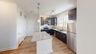 Located at 109 Sweeten Grass Hill in Asheville, NC, this well-designed two-bedroom, two-bathroom residence offers a functional and comfortable single-floor layout. The kitchen is a standout feature, boasting dark cabinetry, granite countertops, a granite-topped center island with pendant lighting, stainless steel appliances including a refrigerator, dishwasher, microwave, and range, plus wood-look flooring and a window that brings in natural light. The open layout connects the kitchen seamlessly to the living areas. The primary bedroom is a generously sized retreat with plush carpeting, a ceiling fan, and direct access to both a walk-in closet with wire shelving and an en-suite bathroom. The en-suite features a tub-shower combination with white tile surround and chrome fixtures. The second bedroom, also carpeted, offers bright windows with views of the surrounding community and ample room for furnishings. The second full bathroom mirrors the first, complete with a tub-shower combo and wood-look flooring. Two closets provide excellent storage throughout. Neutral tones, clean lines, and consistent finishes lend a cohesive, modern ambiance to this Asheville residence.